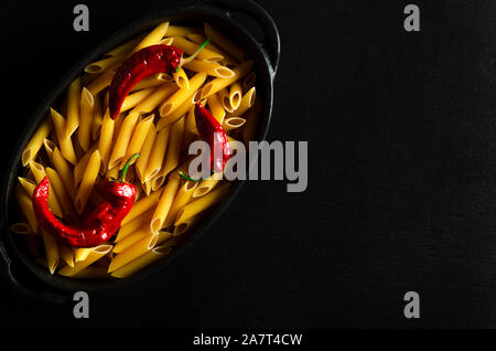 Nudeln mit getrockneten Chilischoten liegt in einem schwarzen Ovalen Backblech Stockfoto