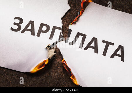 Die Inschrift in Russisch ist Gehalt. Ein brennendes Blatt Papier wird in der Mitte gerissen. Gehalt brennt Stockfoto