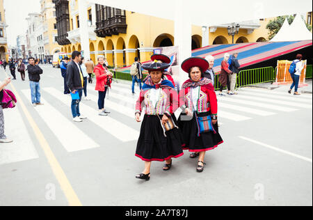LIMA, PERU- circa OKTOBER 2019: Peruanische Damen in traditioneller ländlicher Kleidung, die über den Hauptplatz von Lima laufen Stockfoto