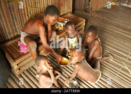 Ilaje Kinder essen als Familie in der ländlichen Gemeinde Idi-Ogba, Ilaje Local Government, Ondo State, Nigeria. Stockfoto