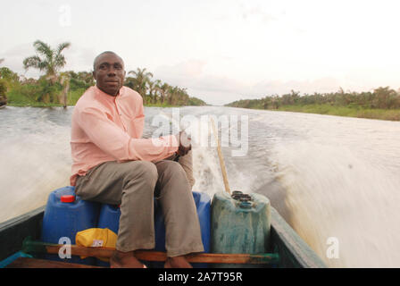 Ein Mann, der sein Boot entlang der Uferpromenade von Ayetoro in der Flussgemeinde der Ilaje Lokalregierung des Ondo Staates zündet. Stockfoto