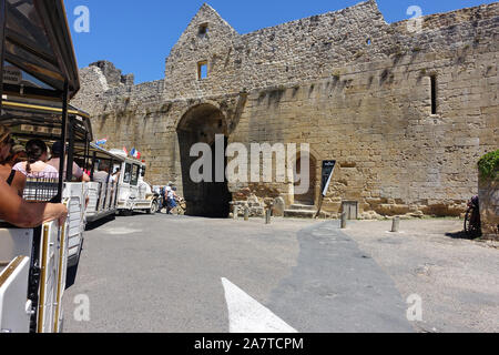 Domme, Frankreich vom 15. Juli 2019: Touristen reiten auf dem kleinen Touristenzug über durch den Turm Tor passieren in der Stadt Domme in Frankreich Stockfoto