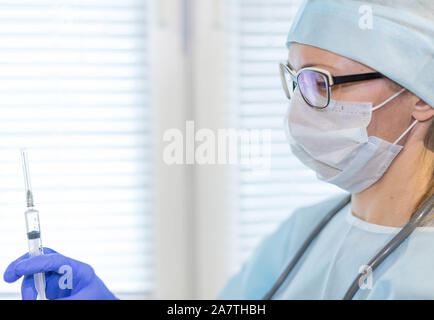 Medizin Gesundheit Hintergrund. Ärztin in der Maske und Handschuhe mit einer Spritze, die mit Medizin, close-up Stockfoto