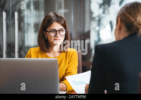 Die Gruppe von Happy business Leute, die am Arbeitsplatz im Büro. Zwei positive Frau, die gemeinsam mit modernen Laptop für die Arbeit Konzept Stockfoto