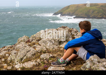 Aa 11 Jahre alter Junge mit Blick über das Meer von Deer Park, Pembrokeshire, Wales. Stockfoto