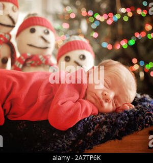 Neugeborene Christmas baby boy Schlafen auf afghanische mit Licht bokeh und Schneemänner im Hintergrund Stockfoto