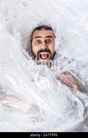 Portrait eines bärtigen Mann in Plastikfolie umwickeln gewickelt. Überrascht, Ausdruck und in der Absicht zu schreien. Stockfoto