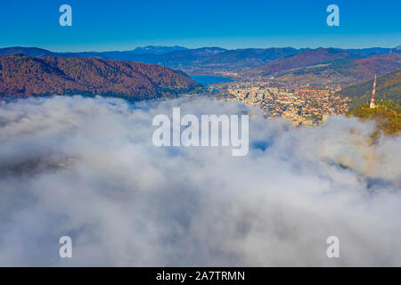 Nebel Wolken kommend über Berg Stadt, Antenne Herbst Landschaft von Piatra Neamt Stadt in Rumänien Stockfoto