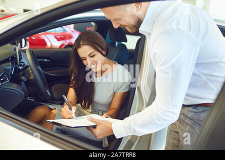Eine junge Frau ein Auto kauft in einem Autohaus. Stockfoto