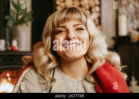 Eine schöne junge Frau in einem Roten Schottenkaro sitzt in einem warmen Classic neues Jahr Innenraum Stockfoto