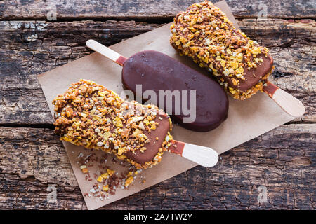 Eis mit Schokolade und Nüsse auf ein Papier auf dem hölzernen Hintergrund Stockfoto