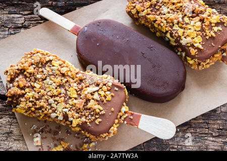 Eis mit Schokolade und Nüsse auf ein Papier auf dem hölzernen Hintergrund closeup Stockfoto