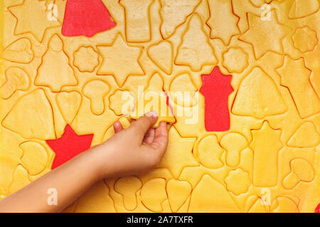 Kinder backen Kekse für Weihnachten. Rohen Teig, Stern, Baum, Bell, Herz, auf einem roten Hintergrund. Ansicht von oben. Stockfoto