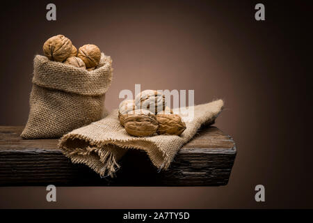 Walnüsse in Jute Tasche auf Holztisch mit dunklen Hintergrund Stockfoto