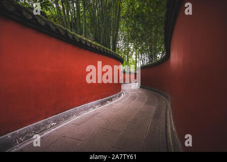 Eine Passage durch Wuhou Schrein in Chengdu, China, ist auf beiden Seiten von hellen roten Wänden flankiert. Stockfoto