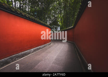Eine Passage durch Wuhou Schrein in Chengdu, China, ist auf beiden Seiten von hellen roten Wänden flankiert. Stockfoto