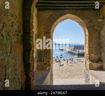 Der Strand und Pier in Cefalú, Sizilien, Italien, wie durch einen Torbogen gesehen. Stockfoto