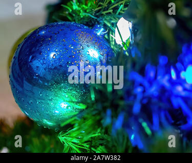 Nasse Weihnachtsverzierungen und Lichter auf einem im Baum Stockfoto