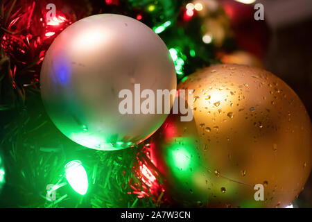 Nasse Weihnachtsverzierungen und Lichter auf einem im Baum Stockfoto