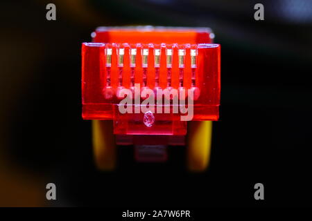 Makro Querschnitt von vorne Gelb RJ45 CAT6 Netzwerk Daten Internet Kabel roter Stecker auf dunklem Hintergrund abgeschirmt Stockfoto