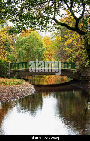 Eine Brücke über den Fluss Brun, im Herbst Farben geschmückt, in Thompson Park, Burnley, Lancashire Stockfoto