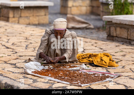 AXUM, Äthiopien, 27. APRIL 2019: alte Frau auf der Straße vor der berühmten Kirche Unserer Lieben Frau vom Zion Räucherwerk verkaufen am 27. April 2019 in Aksum, Ethiop Stockfoto