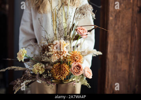 Schönen Herbst Blumenstrauß aus gemischten Blumen mit trockenen Winden in den Händen einer Frau. Die Arbeit der Floristen. Schönen Blumenstrauß. Blume Lieferung Stockfoto