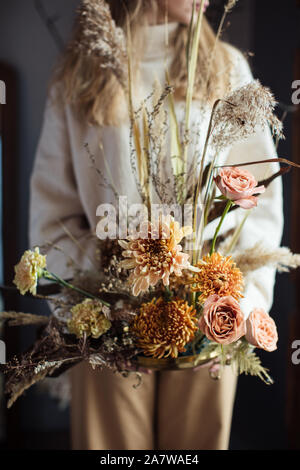Schönen Herbst Blumenstrauß aus gemischten Blumen mit trockenen Winden in den Händen einer Frau. Die Arbeit der Floristen. Schönen Blumenstrauß. Blume Lieferung Stockfoto