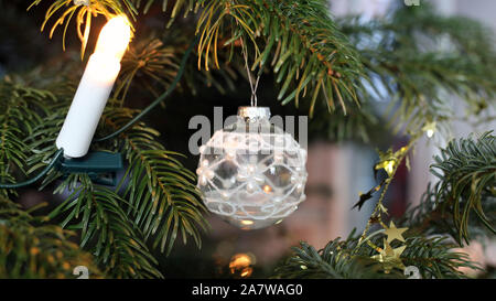 Weihnachtsschmuck hängen von einem Weihnachtsbaum. Schöne weiße Kugel Ornamente und Kerzen für Weihnachten Thema Dekorationen gedacht. Stockfoto