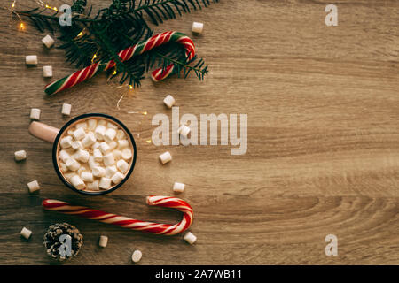 Weihnachten flach mit rosa Tasse Kaffee mit Marshmallows und Bonbons auf hölzernen Hintergrund Stockfoto