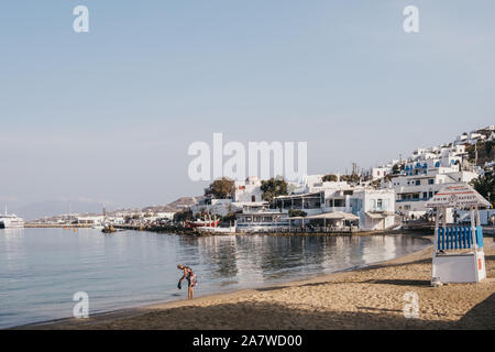 Mykonos Stadt, Griechenland - 20. September 2019: Frau spülen Badeanzug am Strand in Hora, auch als die Stadt Mykonos, Hauptstadt der Insel und einer der Th bekannt Stockfoto