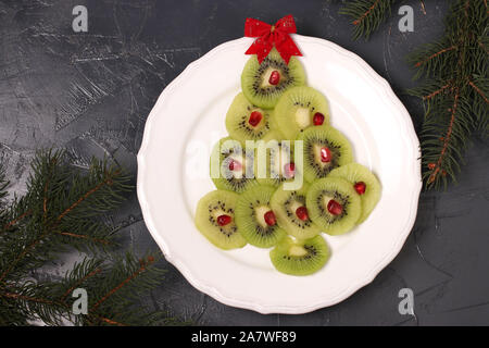 Weihnachtsbaum aus Kiwi und Granatapfel, kreative Idee für Weihnachten und das neue Jahr festlich Speisen, Obst Snack für Kinder Stockfoto