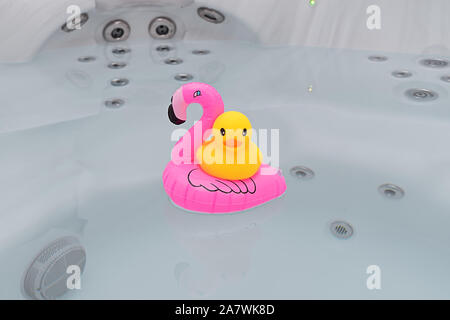 Floating rosa Flamingo mit gelben Gummiente in Whirlpool Badewanne. Schaumbad Party, Sommer Zeit Konzept Stockfoto