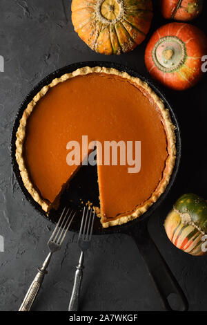 Hausgemachte Pumpkin Pie in gusseisernen Pfanne auf schwarzem Hintergrund oben kopieren. Hygge oder zu Hause backen Konzept oben anzeigen Stockfoto