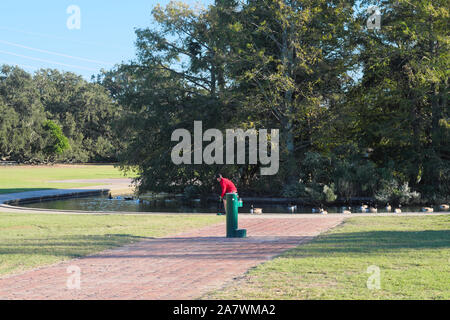 Runner vorbei an grünen Wasser Brunnen in den öffentlichen Park. Stockfoto