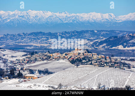 Kleine Stadt auf den Hügeln im Schnee im Gebirge im Hintergrund in Piemont, Norditalien abgedeckt. Stockfoto