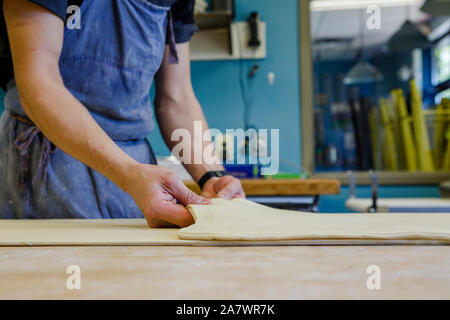 In der Nähe von Bäcker falten Teig auf der bemehlten Arbeitsfläche in der Küche Stockfoto