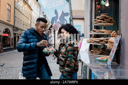 Paar gemeinsame Essen auf der Straße Lächeln und zusammen lachen Stockfoto