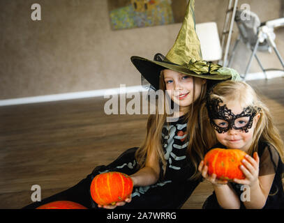 Zwei Schwestern gekleidet im Skelett Kostüme für Halloween mit Kürbissen Stockfoto