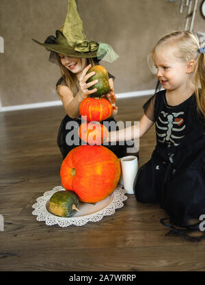 Zwei Schwestern gekleidet im Skelett Kostüme für Halloween mit Kürbissen Stockfoto