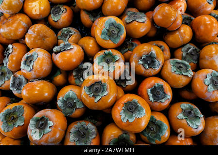 Frische reife Kaki. Organische Kaki Frucht Haufen Bauernmarkt. Persimonen Hintergrund. Stockfoto