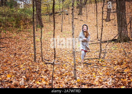 Junge Rote Haare Mädchen spielen im Freien im Herbst Blätter Stockfoto