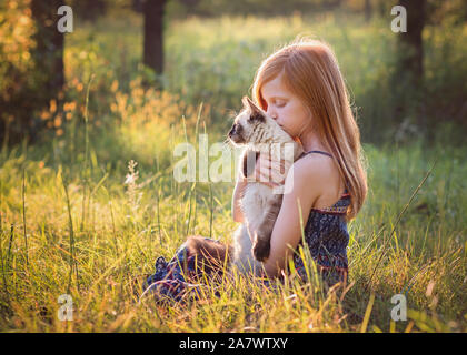 Junges Mädchen mit Katze draußen in der Wiese Stockfoto