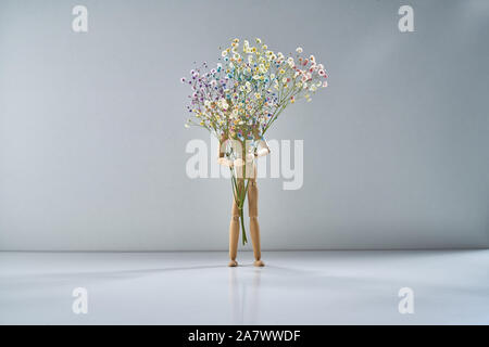 Holz- Mann mit einem Zweig der zarten Blüten auf einem hellgrauen Hintergrund Stockfoto