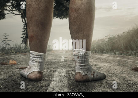 Zurück der schmutzigen, blutigen Füße mit weißen Socken und ein großes Loch auf der Weg in den Abend Sonnenlicht Stockfoto