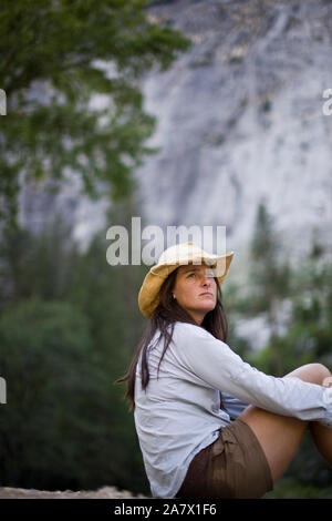 Mitte der erwachsenen Frau sitzend mit ihre Arme um ihre Beine. Stockfoto