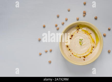 Hausgemachte hummus Bowl mit Kichererbsen und Olivenöl über Hintergrund eingerichtet. Ansicht von oben. Vegetarische gesunde Ernährung Konzept. Stockfoto