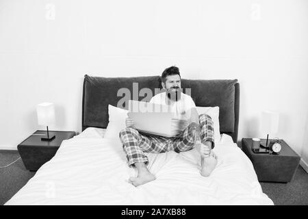 Die späte Stunden. brutale schläfrigen Mann im Schlafzimmer. reife Männer mit Bart im Pyjama auf dem Bett. Schlafen und wach. Energie und Müdigkeit. Geschäftsmann mit Computer. bärtiger Mann hipster Arbeiten am Laptop. Stockfoto