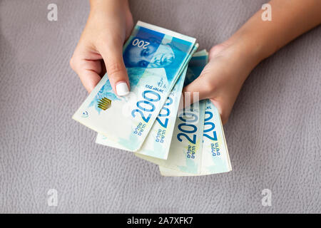 Nahaufnahme von einem Mädchen zählen Israelische Geld. Zählung 200 israelische Schekel Rechnungen - close up auf große Menge Geld. Stockfoto