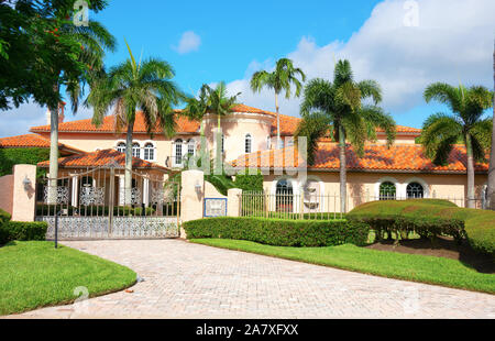 Schönen spanischen Stil luxus Villa Wohnhaus mit einem privacy Tor und Palmen auf einem blauen Himmel sonnigen Morgen.